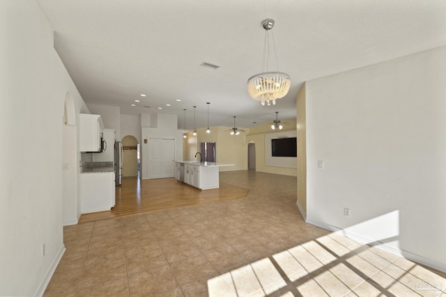 kitchen featuring white cabinets, ceiling fan with notable chandelier, sink, hanging light fixtures, and an island with sink