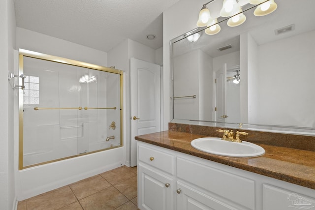 bathroom featuring ceiling fan, tile patterned flooring, a textured ceiling, combined bath / shower with glass door, and vanity