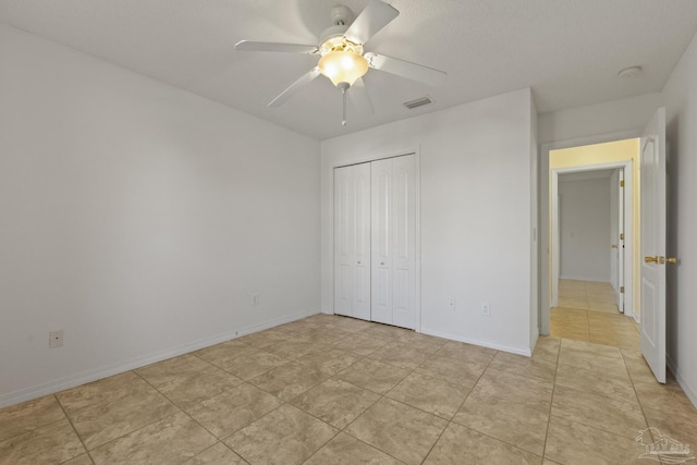 unfurnished bedroom featuring ceiling fan, a closet, and light tile patterned floors