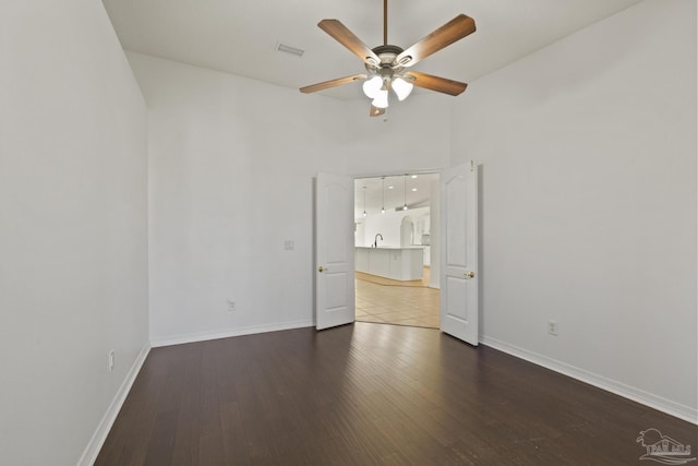 empty room with ceiling fan, dark hardwood / wood-style flooring, a high ceiling, and sink