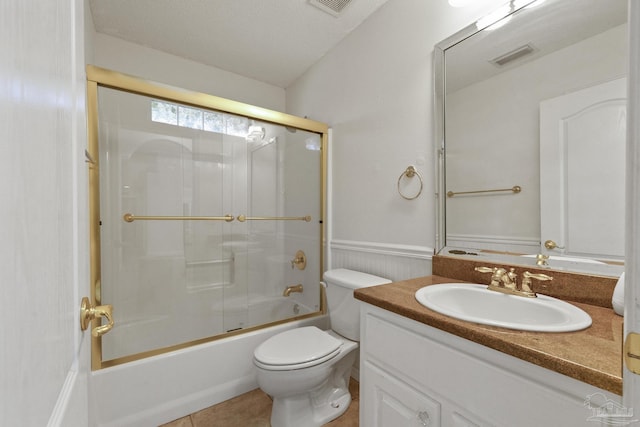 full bathroom featuring toilet, combined bath / shower with glass door, a textured ceiling, and vanity