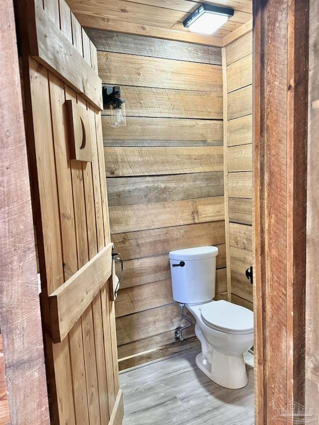 bathroom featuring wooden walls, toilet, and hardwood / wood-style flooring