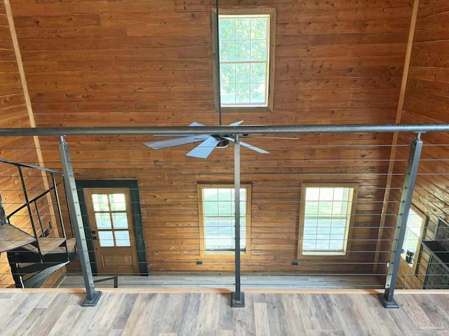 interior details featuring ceiling fan, wooden walls, and wood-type flooring