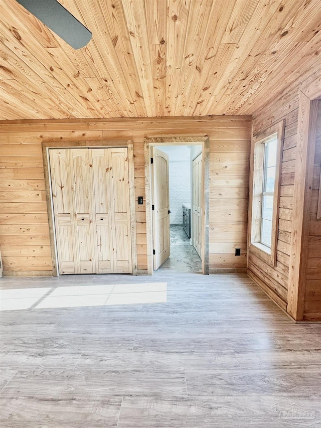 additional living space with light wood-type flooring, wood walls, and wood ceiling