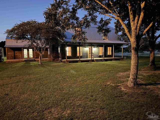 back house at dusk featuring a lawn and french doors