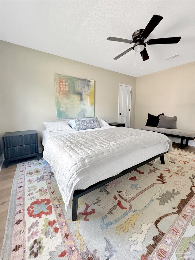 bedroom with a textured ceiling, light hardwood / wood-style floors, and ceiling fan