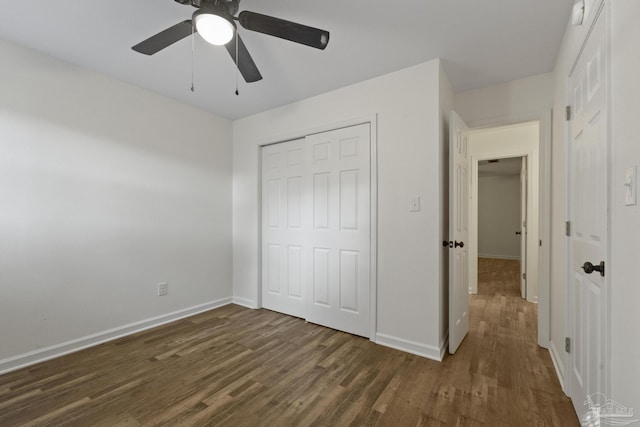 unfurnished bedroom with ceiling fan, dark wood-type flooring, and a closet