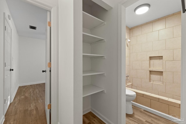 bathroom featuring toilet, wood-type flooring, built in features, and shower / tub combination