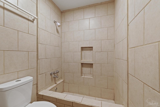 bathroom featuring tiled shower / bath combo and toilet