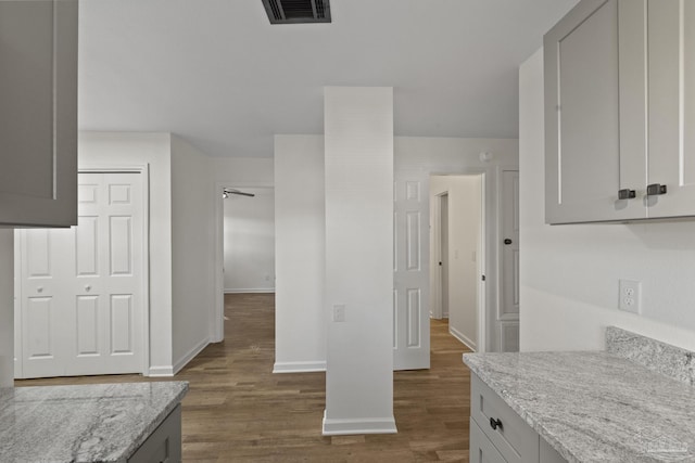 kitchen featuring gray cabinetry, light stone counters, and dark hardwood / wood-style flooring