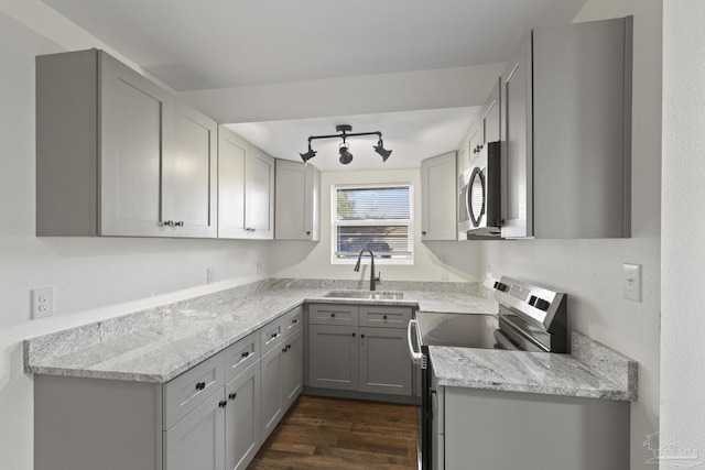 kitchen with sink, stainless steel appliances, dark wood-type flooring, light stone counters, and gray cabinets