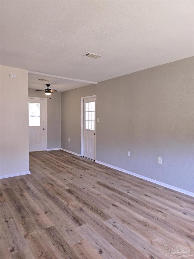 spare room with ceiling fan, light hardwood / wood-style flooring, and a textured ceiling