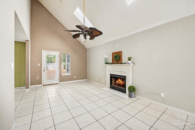 unfurnished living room with a skylight, a textured ceiling, ceiling fan, high vaulted ceiling, and a tiled fireplace