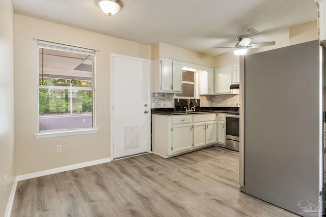 7035 Moore Ave, Pensacola, FL 32526 - kitchen featuring a sink, stainless steel electric stove, freestanding refrigerator, white cabinets, and dark countertops