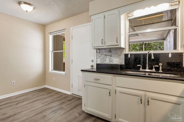 7035 Moore Ave, Pensacola, FL 32526 - kitchen with a sink, white cabinetry, backsplash, dark stone counters, and light wood-type flooring