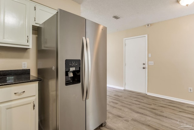 7035 Moore Ave, Pensacola, FL 32526 - kitchen featuring baseboards, light wood-style floors, stainless steel fridge, and dark stone counters
