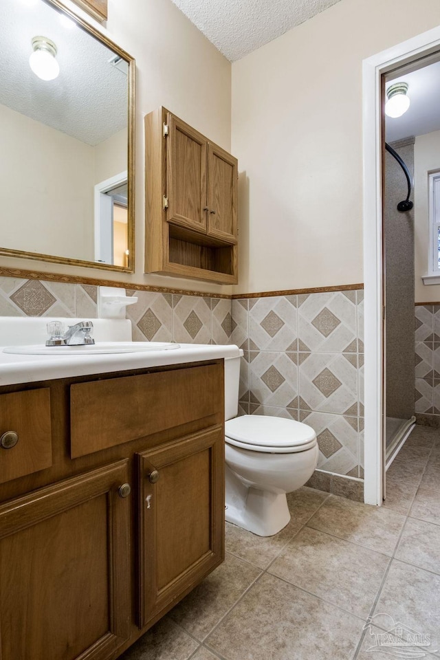 7035 Moore Ave, Pensacola, FL 32526 - bathroom with vanity, tile walls, a textured ceiling, and toilet