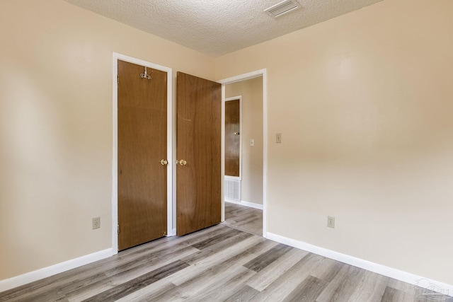 7035 Moore Ave, Pensacola, FL 32526 - unfurnished bedroom featuring a textured ceiling, visible vents, wood finished floors, and baseboards