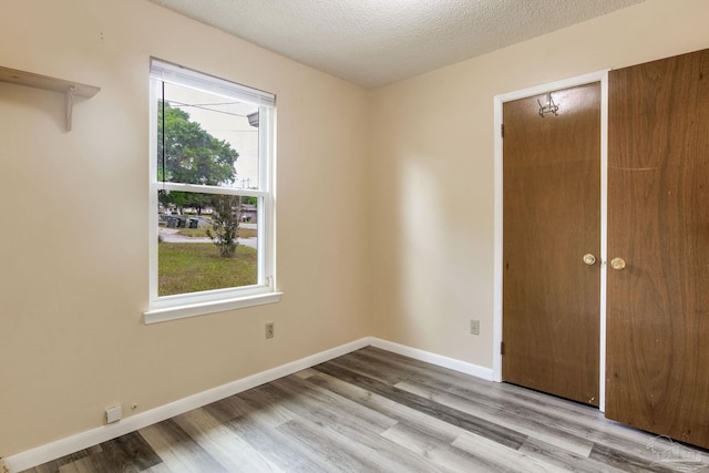 7035 Moore Ave, Pensacola, FL 32526 - unfurnished bedroom with baseboards, a closet, a textured ceiling, and wood finished floors
