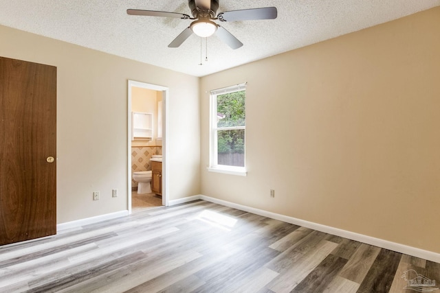 7035 Moore Ave, Pensacola, FL 32526 - unfurnished bedroom featuring ensuite bathroom, a textured ceiling, baseboards, and light wood-type flooring