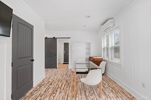 sitting room featuring a wall mounted AC, light hardwood / wood-style flooring, wood walls, a barn door, and ornamental molding