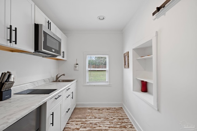 kitchen with sink, white cabinetry, light stone counters, black electric stovetop, and built in shelves