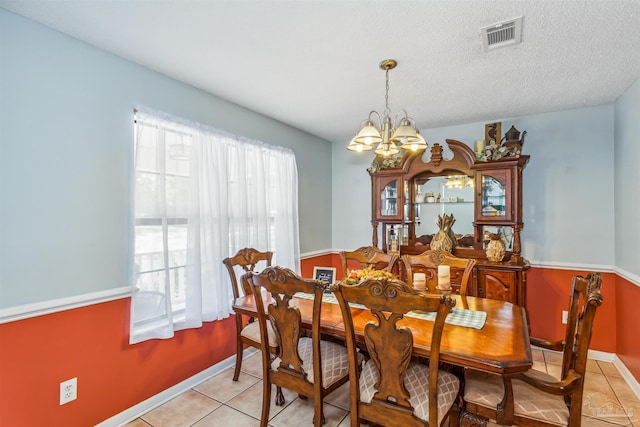 dining room with a textured ceiling, light tile patterned flooring, and a chandelier