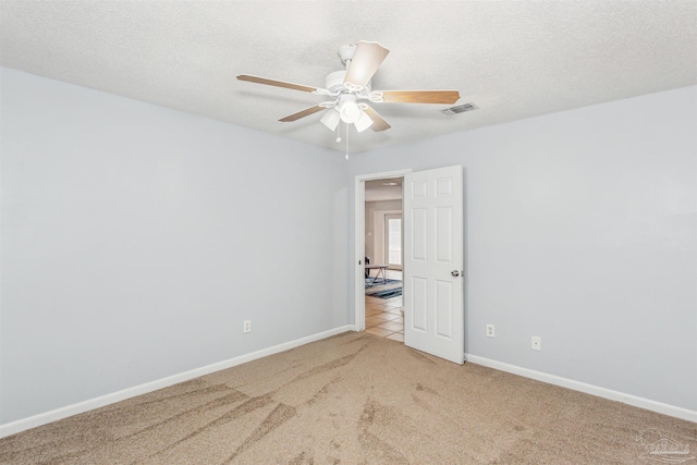 empty room featuring a textured ceiling, carpet floors, and ceiling fan