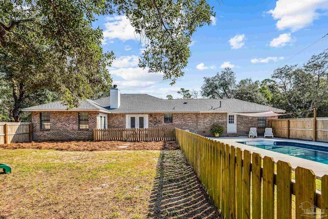 rear view of property with a yard and a fenced in pool