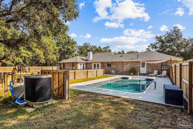 view of swimming pool featuring a patio, cooling unit, and a lawn