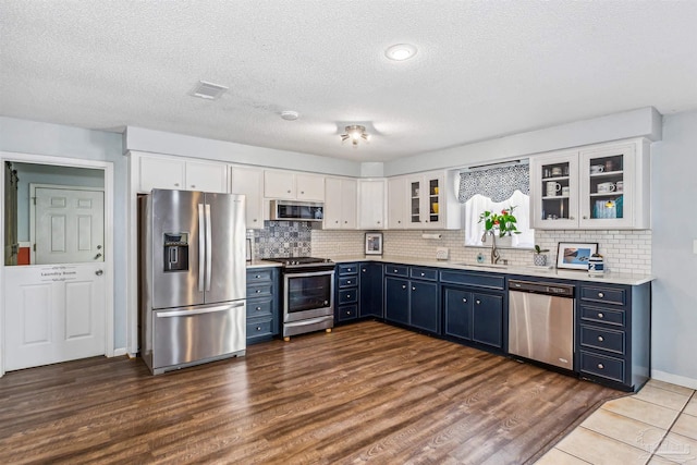 kitchen with white cabinetry, blue cabinetry, dark hardwood / wood-style floors, sink, and stainless steel appliances