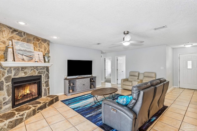 tiled living room with a textured ceiling, a fireplace, and ceiling fan