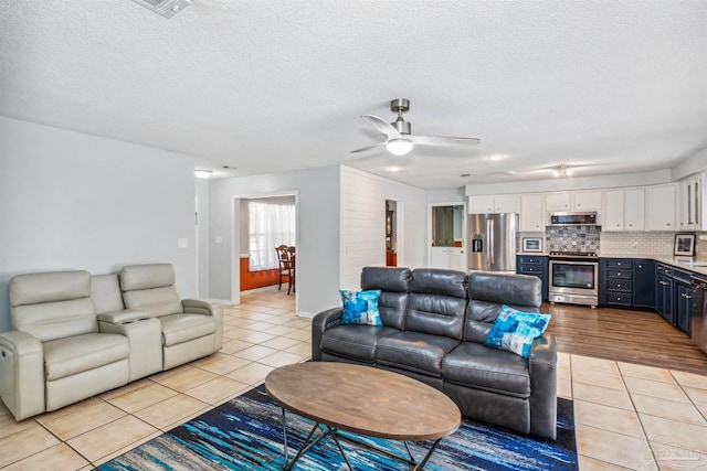 tiled living room featuring ceiling fan and a textured ceiling