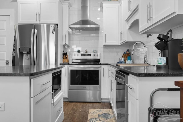 kitchen featuring appliances with stainless steel finishes, dark wood-type flooring, wall chimney exhaust hood, tasteful backsplash, and white cabinets