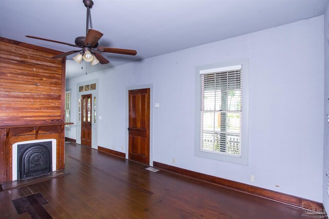 unfurnished living room featuring dark wood-type flooring and ceiling fan