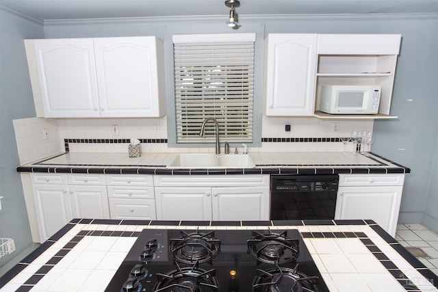 kitchen with sink, white cabinetry, black appliances, tile counters, and backsplash