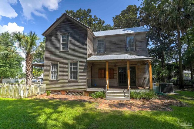 rear view of property with cooling unit, a lawn, and a sunroom