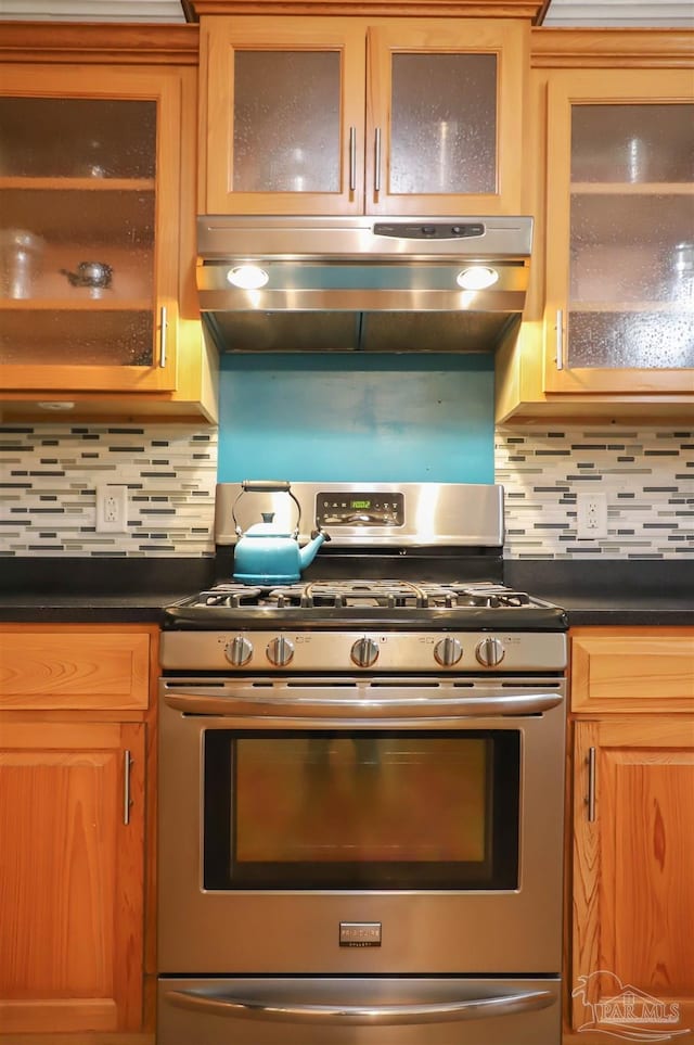 1609 N Spring St, Pensacola, FL 32501 - kitchen featuring stainless steel gas stove, dark countertops, under cabinet range hood, and backsplash