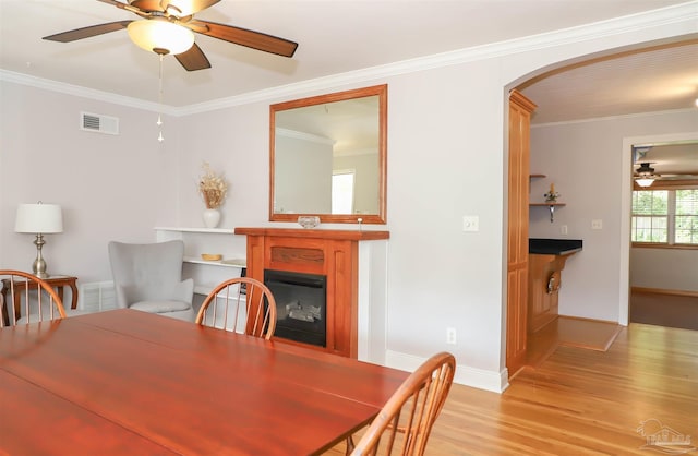 1609 N Spring St, Pensacola, FL 32501 - dining space featuring ceiling fan, a fireplace, arched walkways, light wood-style flooring, and ornamental molding
