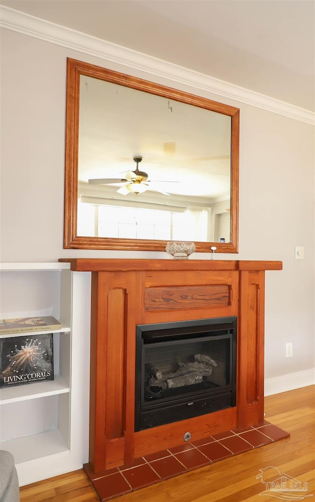 1609 N Spring St, Pensacola, FL 32501 - detailed view of ornamental molding, a fireplace with raised hearth, wood finished floors, ceiling fan, and baseboards