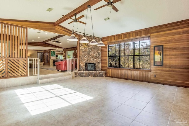 unfurnished living room featuring light tile patterned flooring, vaulted ceiling with beams, a stone fireplace, and wood walls