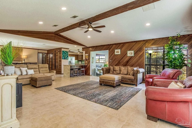 tiled living room featuring vaulted ceiling with beams, a wealth of natural light, wooden walls, and ceiling fan