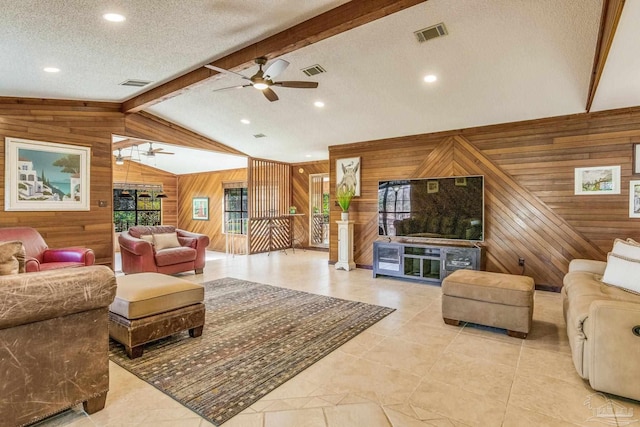 living room featuring a textured ceiling, lofted ceiling with beams, ceiling fan, and wood walls