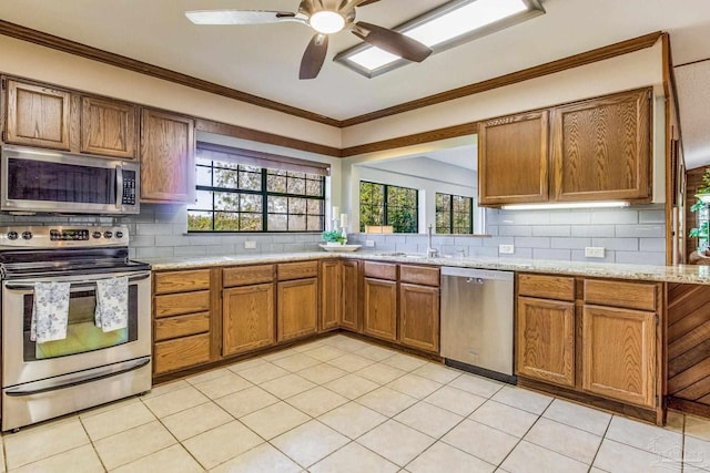 kitchen with decorative backsplash, a healthy amount of sunlight, stainless steel appliances, and ornamental molding