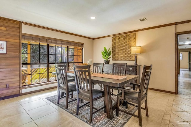 dining room with light tile patterned flooring, ornamental molding, and wood walls