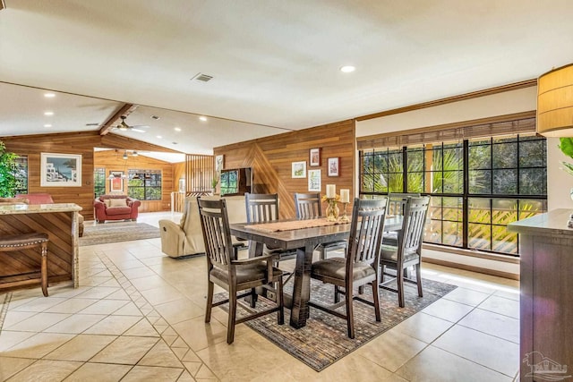 dining space with light tile patterned floors, vaulted ceiling with beams, ceiling fan, and wood walls