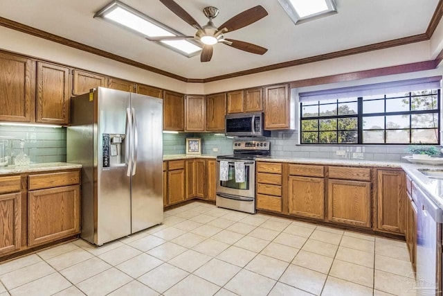 kitchen featuring ceiling fan, appliances with stainless steel finishes, decorative backsplash, light tile patterned floors, and ornamental molding