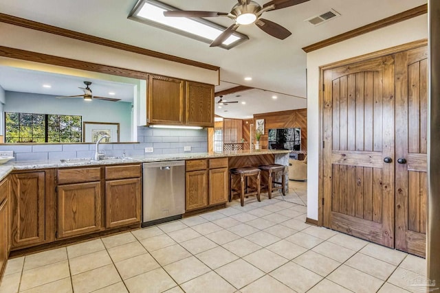 kitchen featuring crown molding, sink, stainless steel dishwasher, decorative backsplash, and light stone counters