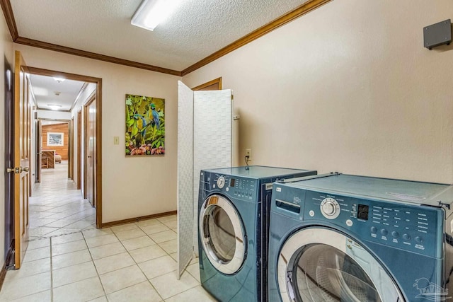 clothes washing area with light tile patterned floors, washing machine and dryer, a textured ceiling, and crown molding