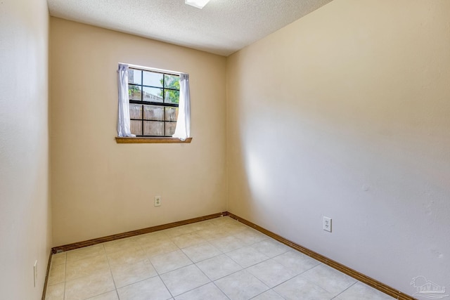 tiled empty room with a textured ceiling